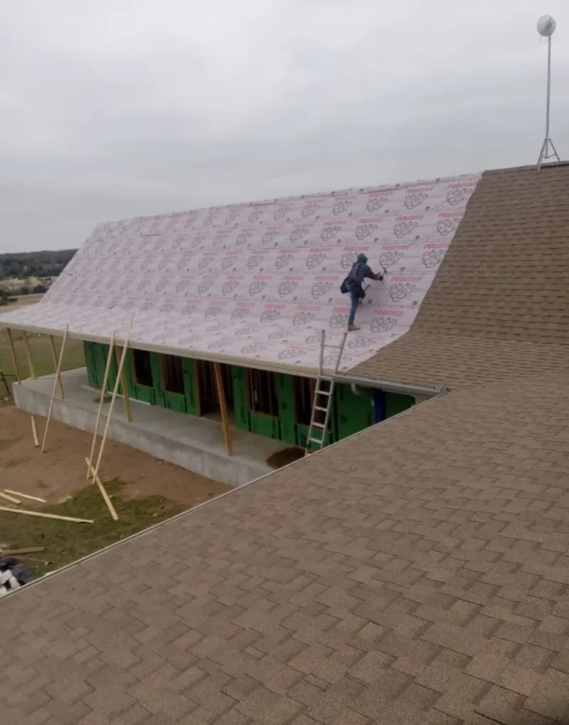 Worker preparing underlayment for a metal roof installation in Fairhope
